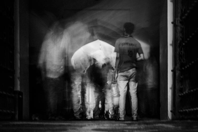 The black and white exposure blurs a visitor across the gateway, leaving the tomb’s distant façade steady behind the moving figure.