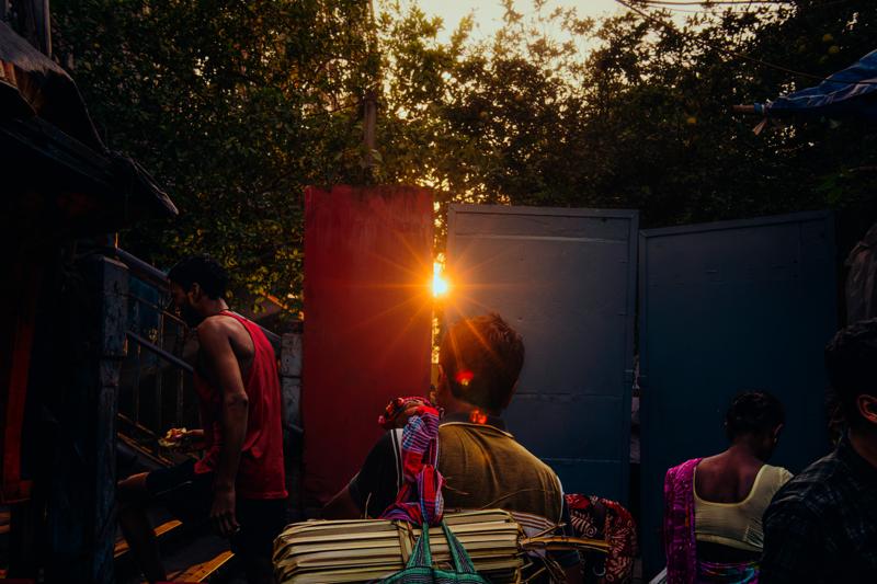 A idol glows above the gathered worshippers, its warm light picking out faces and hands in the otherwise dark street.