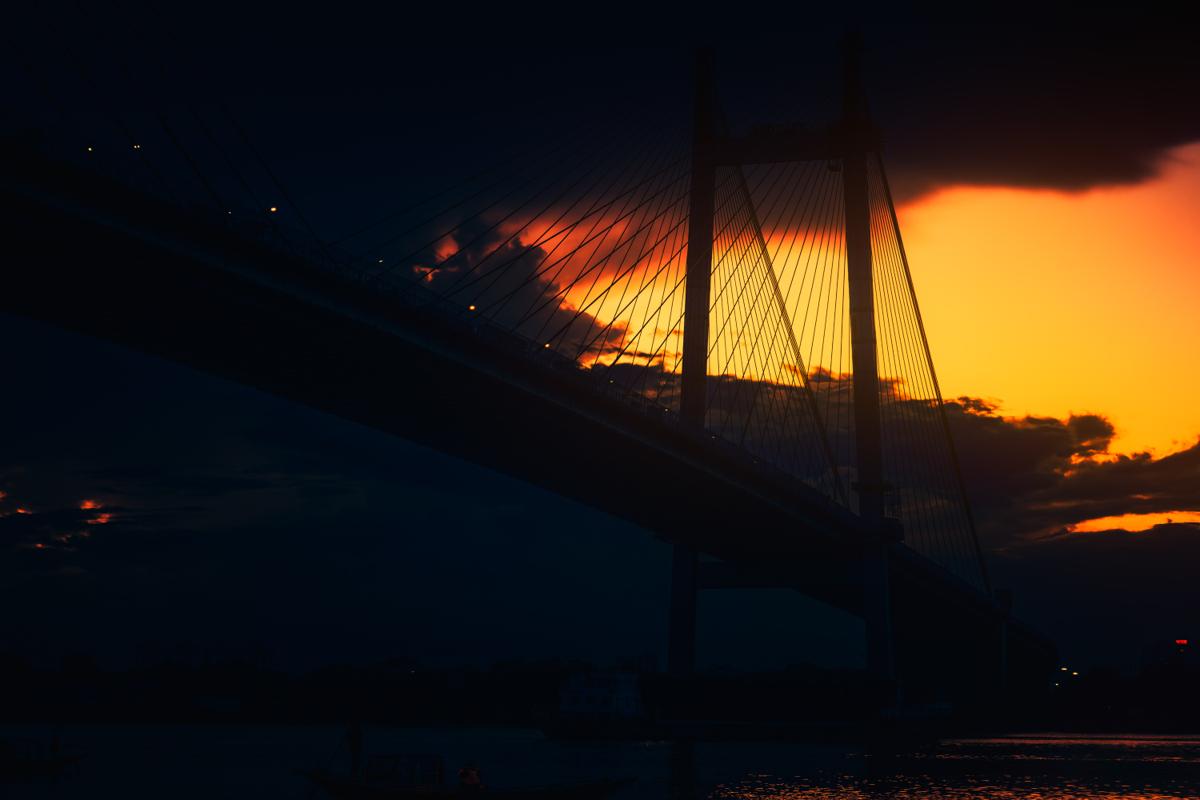 The towers and cables of Vidyasagar Setu rise in silhouette against a golden sunset at Kolkata’s Princep Ghat.